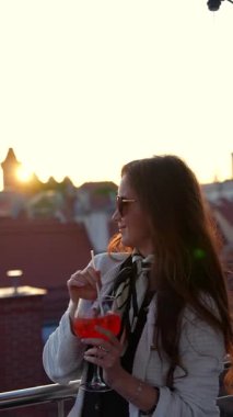 Çatıda Poznan eski kasaba manzaralı kokteyl tutan genç bir kadın.