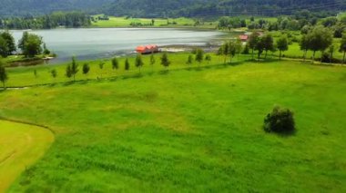 Aerial view of summer meadow tree lake boathouses and hills
