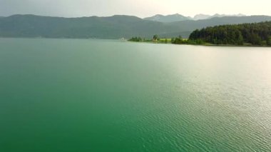 Aerial view of calm alpine lake with forest hills and mountains