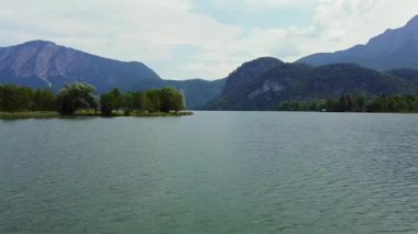 Calm mountain lake with blue water peninsula and forested peaks