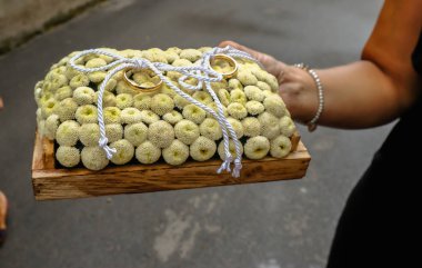 Altın alyans krem çiçek yatağı üzerinde düzenlenmiş çifti. Yüzük yerinde yay beyaz kablosu ile bağlanmıştır.