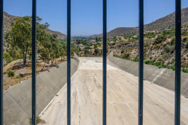 Parlak mavi gökyüzü gün erken yaz aylarında taşması Germasogeia Barajı. Atış savak adlı ve sahile doğru Vadisi parmaklıklar bakan alınır