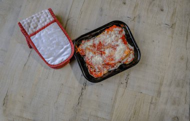 Aubrgine ve pişmemiş tabak ve masada bir soluk gri, fırına koymaya hazır bir fırın eldiveni