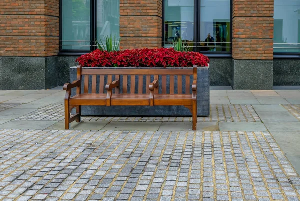 Polierte Holzbank Mit Drei Sitzplätzen Vor Einem Blumenkübel Rote Und — Stockfoto