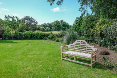 Kırsal manzaralı ve ahşap bankile sakin İngiliz kır bahçesi