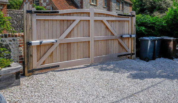 Large wooden entry electric gates with stone driveway. 