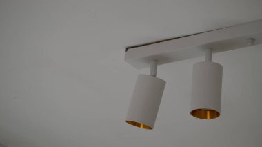 Modern tavan ışıkları, çağdaş bir evin tavanına monte edilmiş beyaz ve altın kaplamalı. İç tasarım, yenileme, ev geliştirme, aydınlatma çözümleri, inşaat ve modern yaşam tarzı kavramları için kullanışlı.