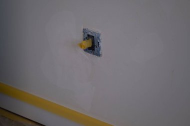 Tamir ve yenileme işlemi sırasında sarı bantla kaplanmış elektrik prizinin kapağını kapatın. DIY, inşaat, güvenlik, içişleri, elektrik ve emlak projeleri için harika.