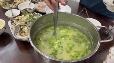 Ot dolu tavuk çorbası, restoranda siyah bir tabakta krema çorbasını süsleyen bir tencere şefinin elinden dökülen bir tabağa dökülüyor. Krema çorbası servis etmek için dekore edildi. Yüksek kalite 4k