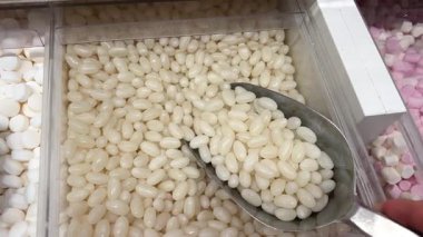 Yavaş Çekim: Renkli Jöle Fasulyeleri Yansıtıcı Beyaz Yüzeye Düşüyor ve Dağılıyor. Tatlı Şeker Arkaplanı. Yüksek kalite 4k görüntü