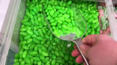 Yavaş Çekim: Renkli Jöle Fasulyeleri Yansıtıcı Beyaz Yüzeye Düşüyor ve Dağılıyor. Tatlı Şeker Arkaplanı. Yüksek kalite 4k görüntü