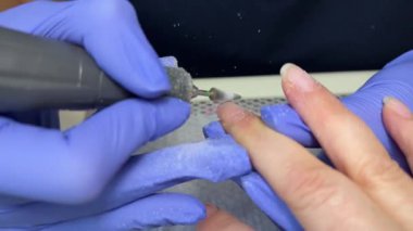 Manikür ustası eldivenler içinde müşterilerinin tırnaklarına kırmızı jel sürerek güzellik salonunu boyuyor. Kadın elleri için profesyonel bakım. Güzellik salonu. Tırnak bakımı tedavisi. Yüksek kalite 4k görüntü