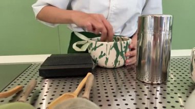 Geleneksel Japon töreninde güzel yeşil çay tozu çırpan bir kadının yaptığı kibrit çayı. Sakinleşme ayini denge, farkındalık ve doğal tatlara odaklandı. Kültürel mirasa derinden bağlıydı..