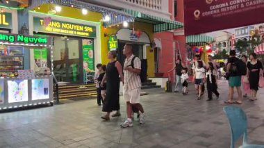 Akşamları turistler dükkanın yakınındaki caddelerde yürürken Asyalı ve Avrupalı insanların Grand World mağazalarına bakıyorlar. Vietnam Phu Quoc Adası 09.05.2025