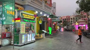 Akşamları turistler dükkanın yakınındaki caddelerde yürürken Asyalı ve Avrupalı insanların Grand World mağazalarına bakıyorlar. Vietnam Phu Quoc Adası 09.05.2025