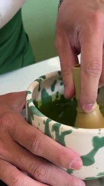 Bambu çırpıcı ile taze yeşil çay demlemek için geleneksel Japon usulü çay çırpmak köpüklü dokular ve sakin deneyimler yaratır. Yüksek kalite 4k görüntü