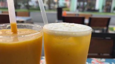 Tropikal bir plaj otelindeki masada iki bardak taze mango suyu. Yüksek kalite 4k görüntü