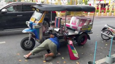 Bir Asya ülkesinde geleneksel bir Tuk Tuk 'u anahtarı çevirirken motoru çalıştırmak için manivela kullanarak çalıştırmak çok zor. Tayland Bangkok 09.11.2025
