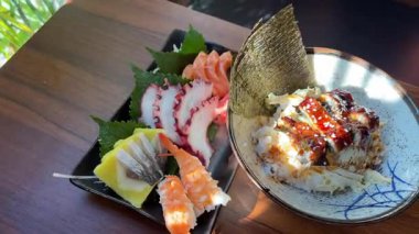 Japon suşi tabağından bir dilim ton balıklı sashimi. Stüdyo ışıkları altında siyah bir arka planda somon, deniz tarağı, yumurta ve garnitürle. Yüksek kalite 4k görüntü