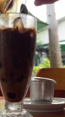 Vietnam kahvesiyle konsantre süt baristasını karıştırıp bir bardak buzlu kahveye karıştırın, yavaş çekimde. Yüksek kalite 4k görüntü
