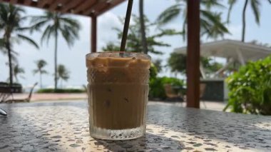 Sabahın erken saatlerinde denizde buzlu kahveyi kapatıyoruz, okyanus kıyısında latte yapıyoruz. Bej kapsül kahve makinesi şeffaf kupa ya da buzlu fincan kahve yapar. Kumsalda dinleniyor..