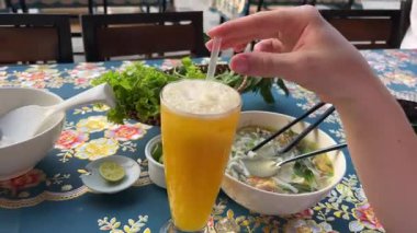 Otantik Burma hindistancevizli şehriye çorbası ve taze otlar. Asya mutfağı, canlı tatlar, kültürel yemek deneyimi. Açık havada tropikal meyve içeceği ve aşçılık lezzeti ile yemek. 4k