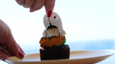 Soldan sağa zenital tavada Cadılar Bayramı şeklinde kurabiyeler, fincanlar ve kabak motifli tabaklar görülüyor. Kurabiyelere odaklı sıcak ve sonbahar kompozisyonu. Hayalet kurabiye.