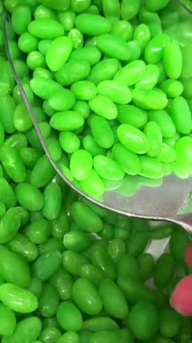 Yavaş Çekim: Renkli Jöle Fasulyeleri Yansıtıcı Beyaz Yüzeye Düşüyor ve Dağılıyor. Tatlı Şeker Arkaplanı. Yüksek kalite 4k görüntü