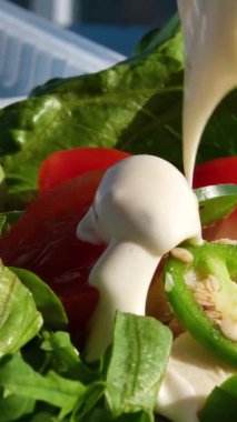 Kadın şef taze bebek salatasını karıştırıp cam üfleme içine salata sosu döker. Organik sebzeler yeşil salatayı cam kasede karıştırıyor. Kahvaltı taze salata ve temiz sebze. Yüksek kalite 4k görüntü