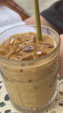  Deniz manzarası, bir kadın ferahlatıcı bir içecek içiyor, bir bardak soğuk kahve ile su damlacıkları ve masada bardaklar. Yüksek kalite 4k görüntü