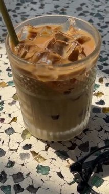  Deniz manzarası, bir kadın ferahlatıcı bir içecek içiyor, bir bardak soğuk kahve ile su damlacıkları ve masada bardaklar. Yüksek kalite 4k görüntü