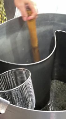 Asyalı bir anne büyük bir tencerede özenle makarna pişirir, suyu köpüklü olana kadar kaynatır, yemek için mükemmel bir donanmanın sinyalini verir. Yüksek kalite 4k görüntü