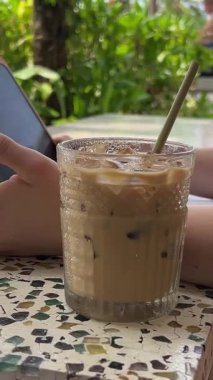 Serbest çalışan kadın eller tabletinde stilus ile resim çizer kafeteryada okyanus manzaralı buzlu kahve. Sahildeki restoranda grafik tasarımcısı çalışıyor. Uzak mesafedeki kadın .