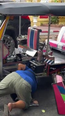 Bir Asya ülkesinde geleneksel bir Tuk Tuk 'u anahtarı çevirirken motoru çalıştırmak için manivela kullanarak çalıştırmak çok zor. Tayland Bangkok 09.11.2025