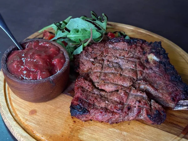 Bir aşçı arkasını döner ve arka bahçedeki kömür ızgarasına taze ızgara biftek koyar. Lezzetli yemek, yakın plan yemek, açık havada yemek yapmak için. Biftek pişirme süreci