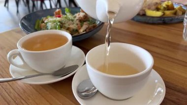 Bir kadın bir sürahide çayını bardağa doldurur. Kahvaltı konsepti. Çay zamanı. Yüksek kalite 4k görüntü