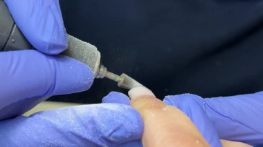 Tırnak törpüleme ustası, adım adım jöle sürüyor. Manikürcü, tırnak törpüsü kullanıyor. Önce matkapla, tırnağı uçla sök ve çubukla it. .