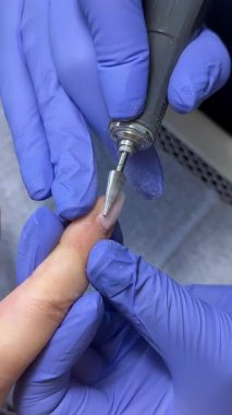 Tırnak törpüleme ustası, adım adım jöle sürüyor. Manikürcü, tırnak törpüsü kullanıyor. Önce matkapla, tırnağı uçla sök ve çubukla it. .