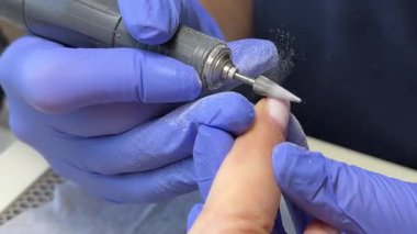 Güzellik uzmanı yüz kalkanı ve eldiven takıyor. Manikür yapmak için elektrikli tırnak matkabı kullanıyor. Güzellik salonunda, iç mekanı ağır çekimde. Yüksek kalite 4k görüntü