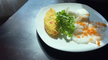 Sarı omlet ve yeşil yapraklı sebzeli bir tabak yemek. Tabak beyaz ve yemek düzgünce düzenlenmiş. Yüksek kalite 4k görüntü