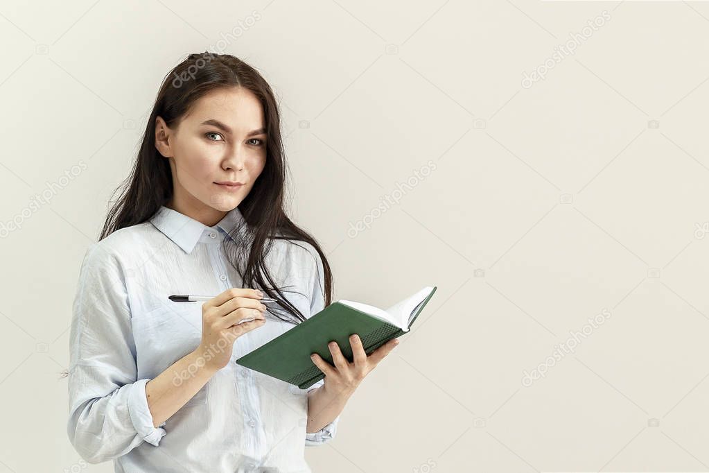 Young beautiful girl with a diary, a notebook and a pen in her hands