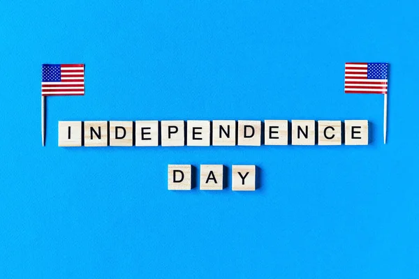 Independence Day inscription in wooden letters on a blue background. Happy Independence Day. The 4th of July. USA Independence day. American flags. copy space. top view