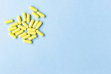 Mavi arka planda sarı kapsüller. Omega-3 vitaminleri. Yiyecek takviyesi. Kapsüllerde balık yağı. Boş alan. Metin için boşluk. kopyalama alanı. Arka plan bulanık. Seçici odaklanma. Pankart. Tıp konsepti.