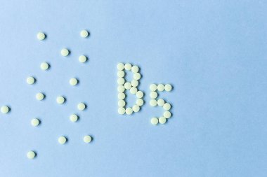 Sarı tabletler mavi arkaplanda B5 oluşturuyorlar. Vitamin kompleksi. Kavram, sağlık, sağlıklı beslenme. İlaçlar. Sağlıklı bir yaşam tarzı. Yiyecek katkı maddesi. kopyalama alanı. Yumuşak odaklanma. Arka plan bulanık. poster