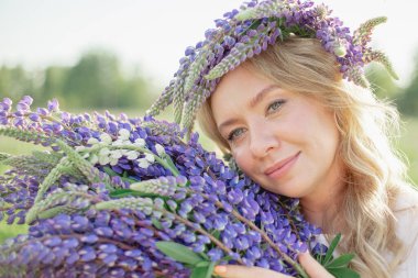 Güzel bir kız elinde bir buket lupin çiçeği tutar ve çiçeklerin kokusunu içine çeker. Alerjilerden arınır, doğanın ve kaplıcanın tadını çıkarır, dinlenir.