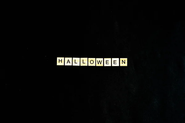 Slova Halloween. Dřevěné bloky s nápisem na černém pozadí zdobené dýněmi. Pohled shora, plochý. Šťastný Halloween — Stock fotografie