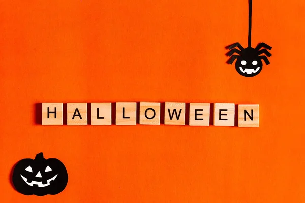 Letras de Halloween sobre fondo naranja con siluetas de papel negro, murciélagos, calabaza, araña. El concepto de Halloween. la vista desde la parte superior —  Fotos de Stock