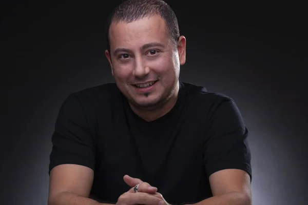 man posing for camera, shaved hair, italian ethnicity, black shirt, studio light, neutral background