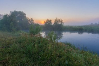 Sabaha karşı, yaz sabahı sisli bir gölde şafak sökerken. manzara.