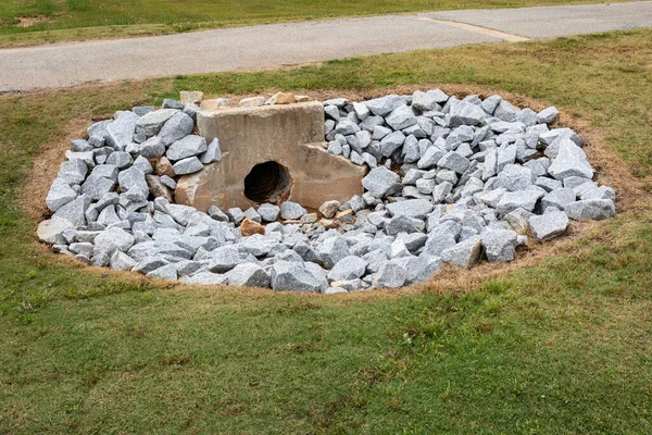 Yeni kayalar, çevre güvenliği, yeşil çimen kopyalama alanı ve yatay görünüm ile çevrili fırtına suyu akıntısı için yıllanmış beton başlık.